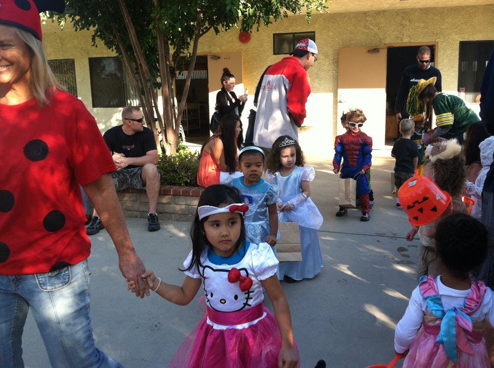 Person in ladybug costume holding hands with child in Hello Kitty costume
