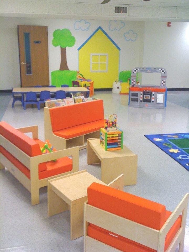 Children's play area with orange cushioned seating and a wall mural