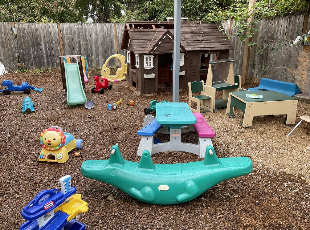 Outdoor playground with a playhouse, slide, and various toys