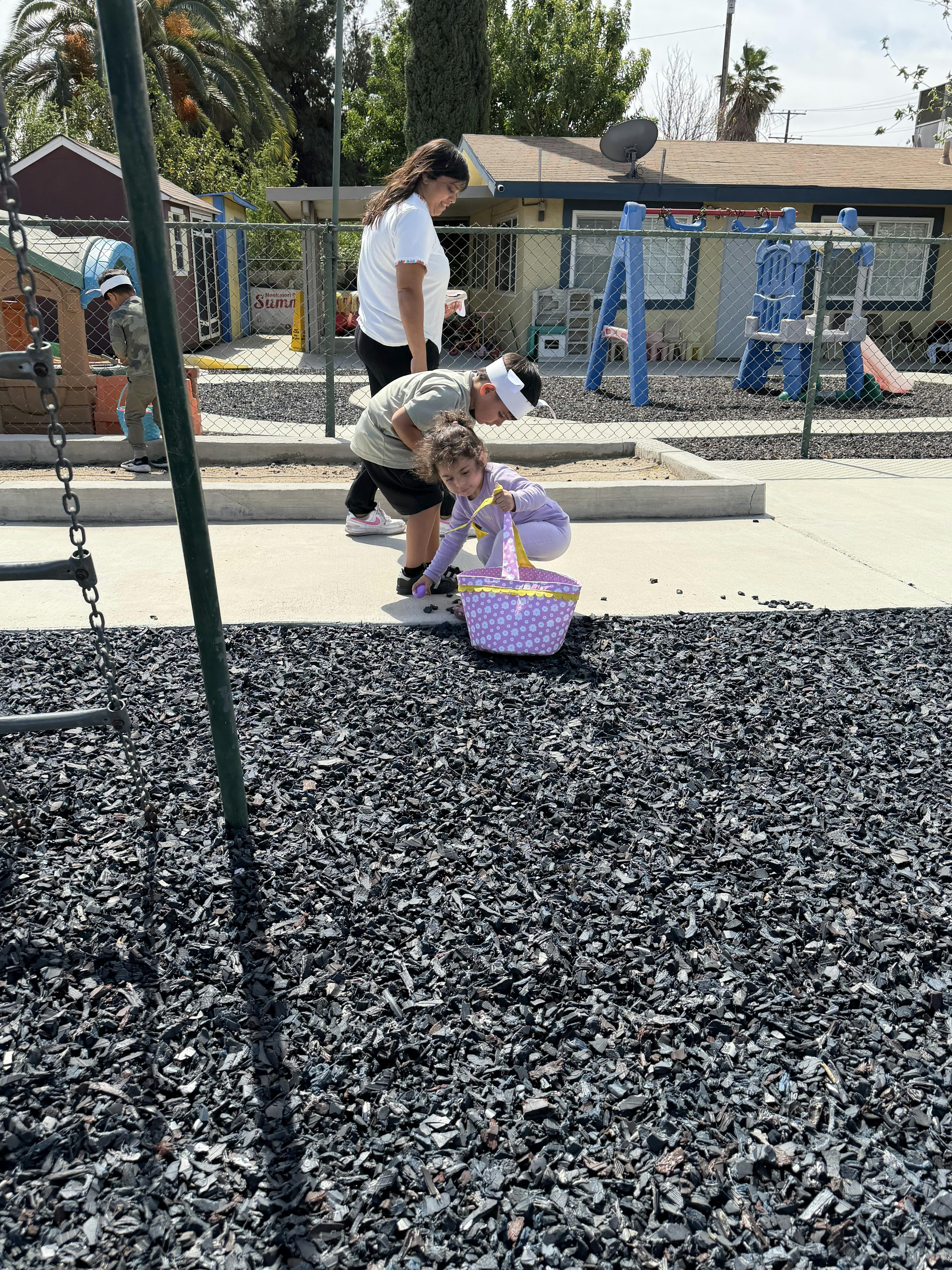 Children gathering eggs in baskets at a playground