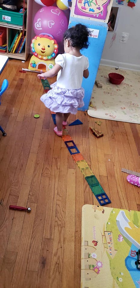 Child walking on a line of colorful magnetic tiles on a wooden floor