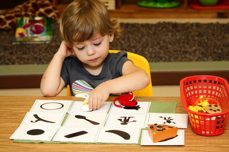 Child playing with shape matching cards at a table