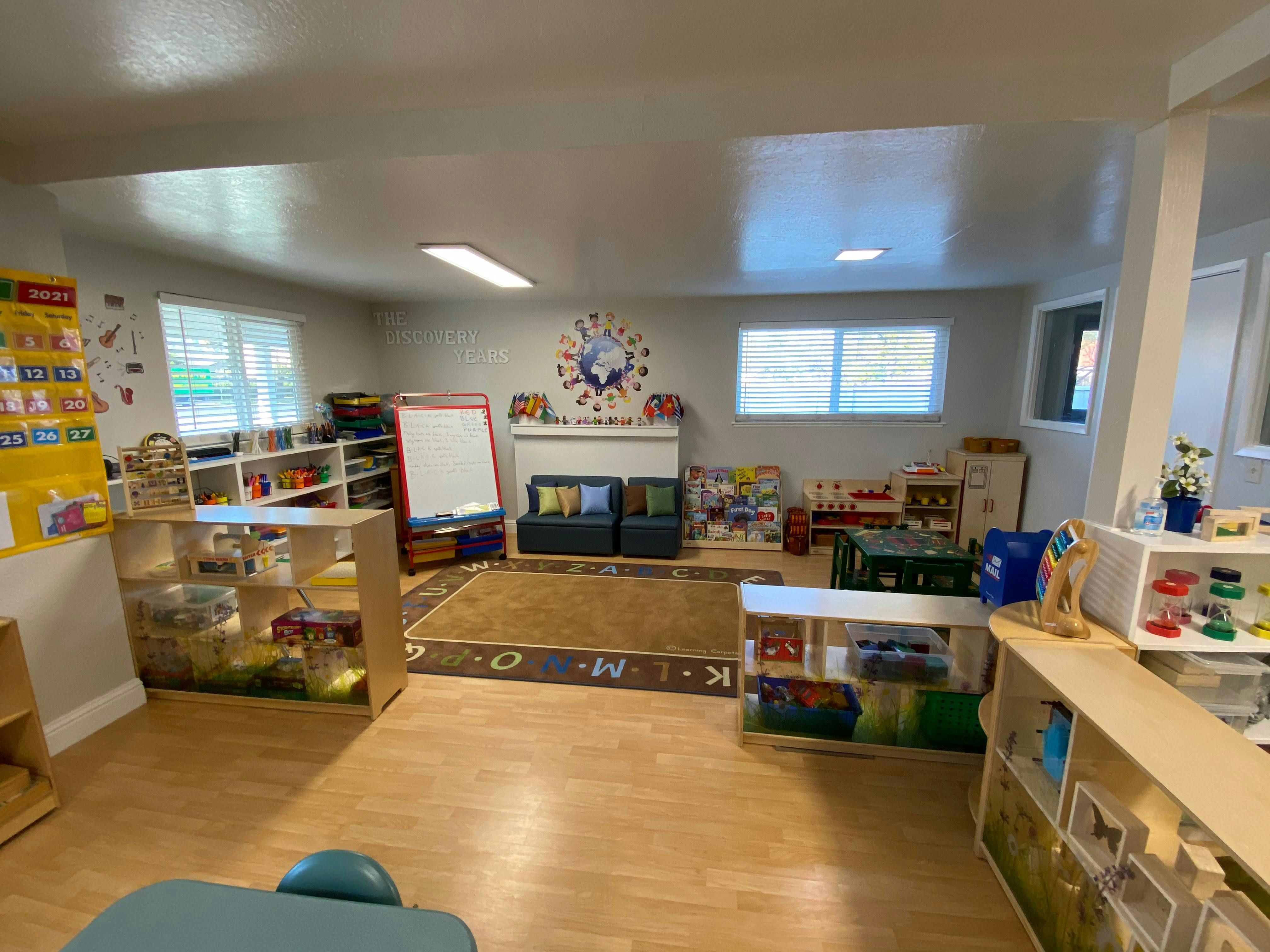 Classroom with play areas, shelves, and small furniture