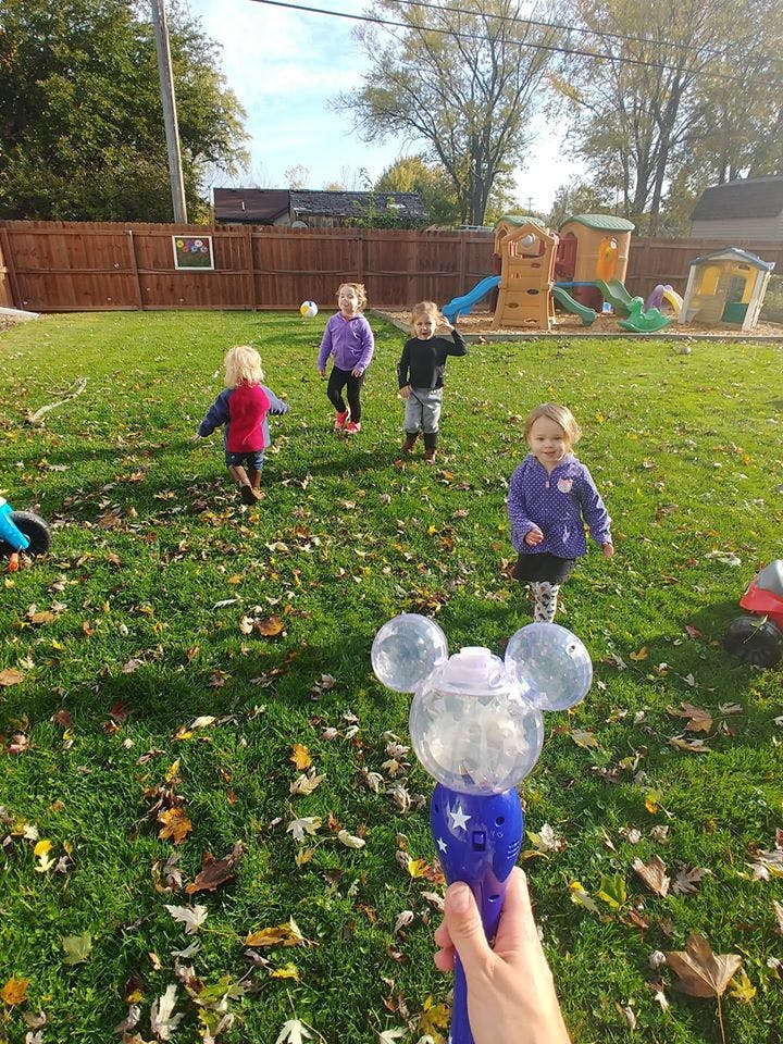Children playing in a grassy yard with a playground in the background