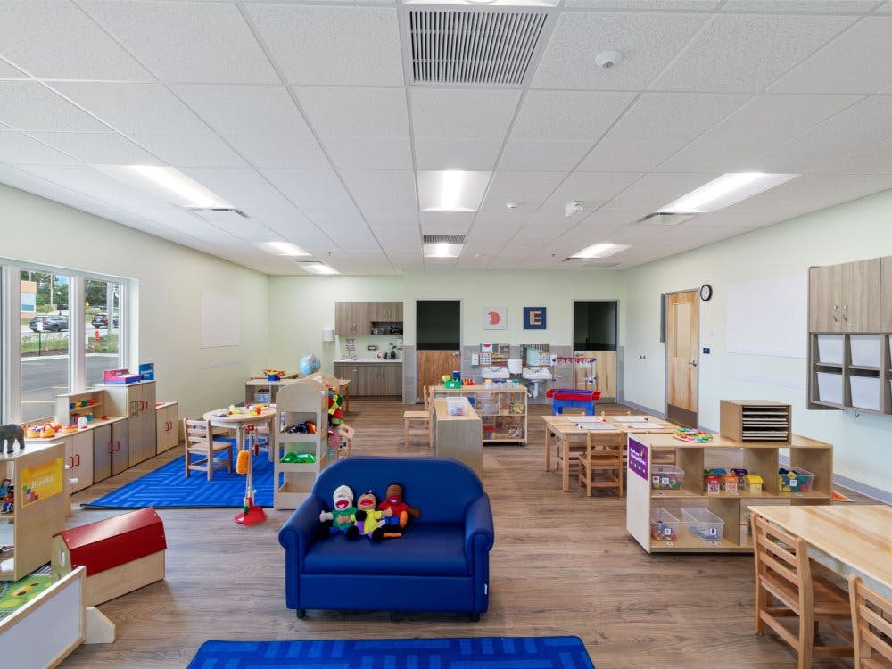 Empty classroom with small tables, chairs, and play areas