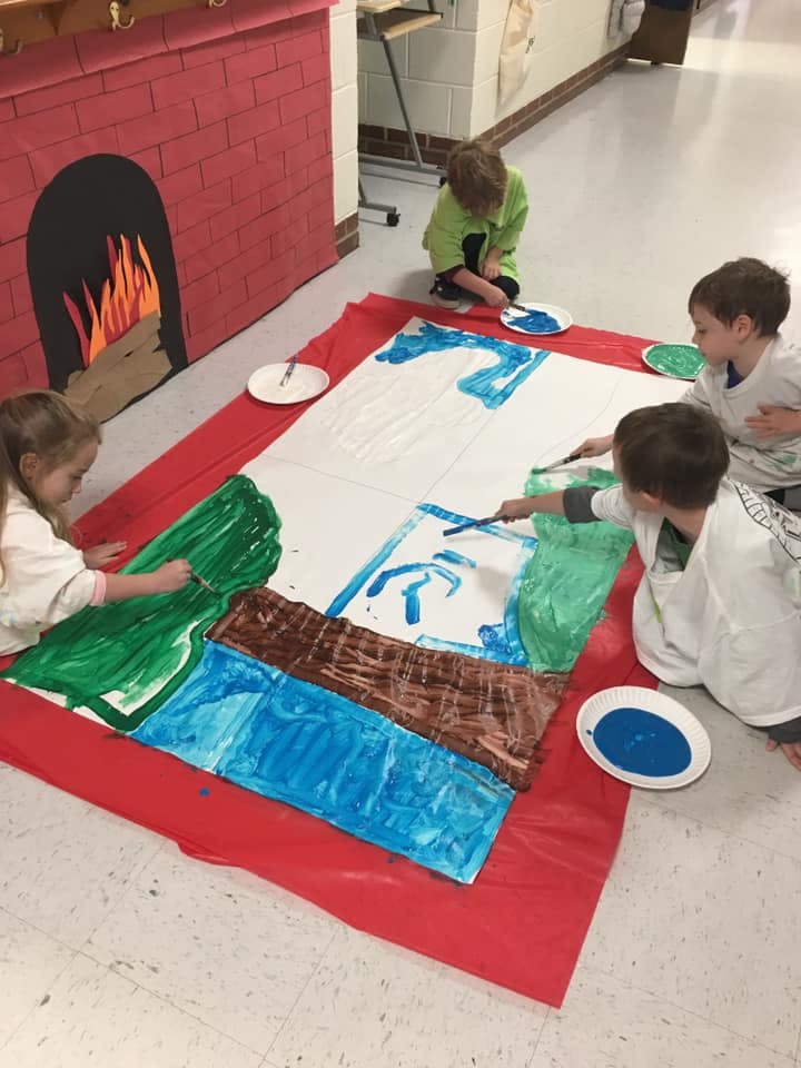 Children painting on a large sheet of paper on the floor