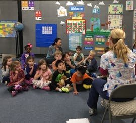 Adult speaking to a group of children in a classroom