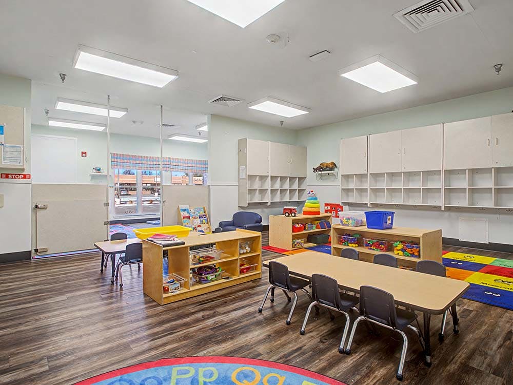 Classroom with child-sized tables and chairs, cubbies, and shelves of toys