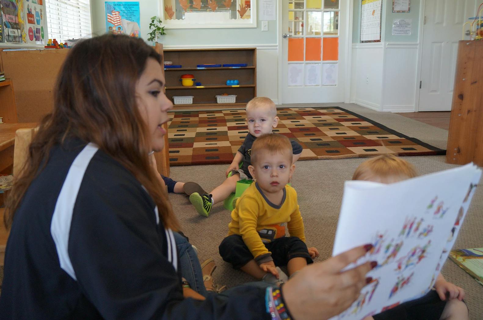 Person reading a book to children in a classroom