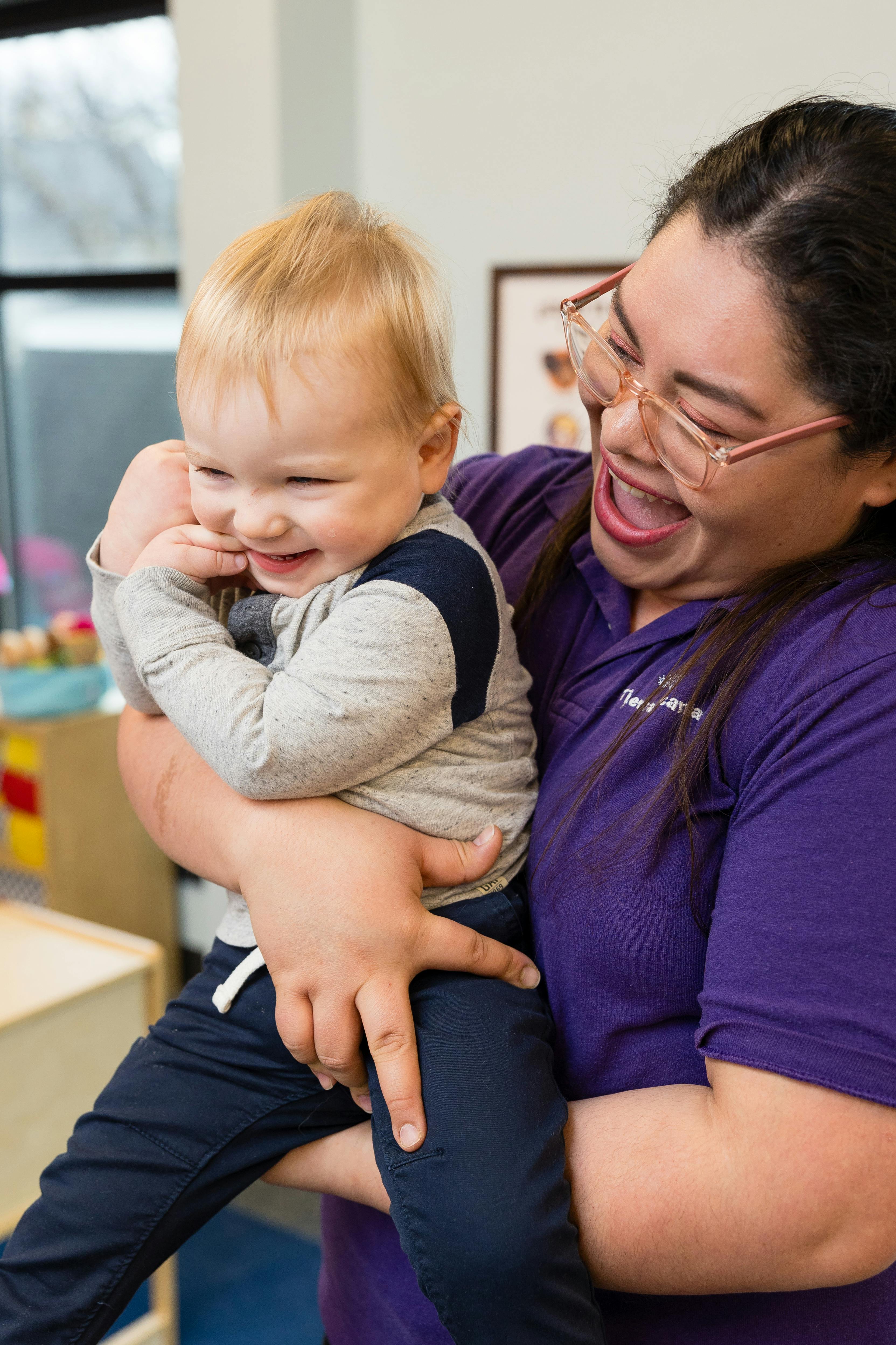 Adult holding a child, both looking at each other and smiling