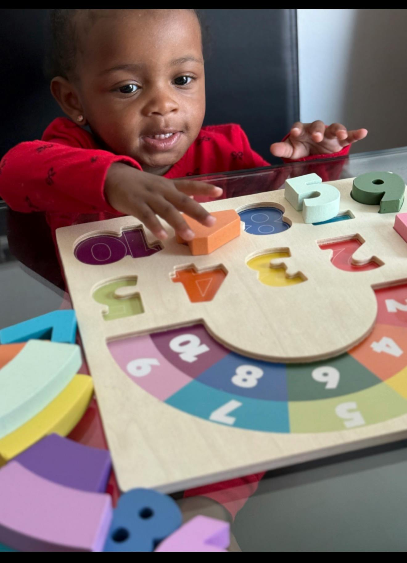 Child playing with a wooden number puzzle at a table