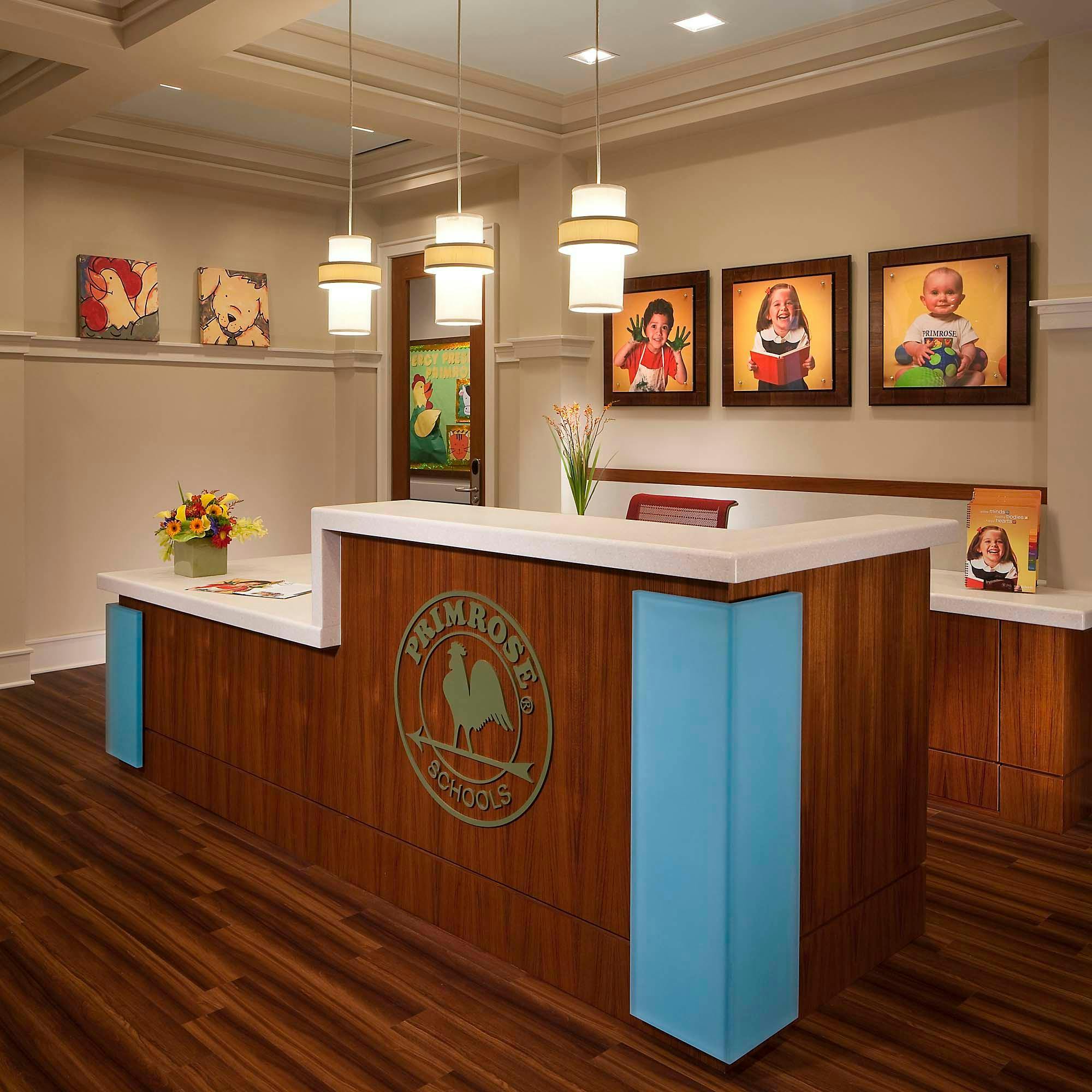 Reception desk with a logo and framed photos of children on the wall