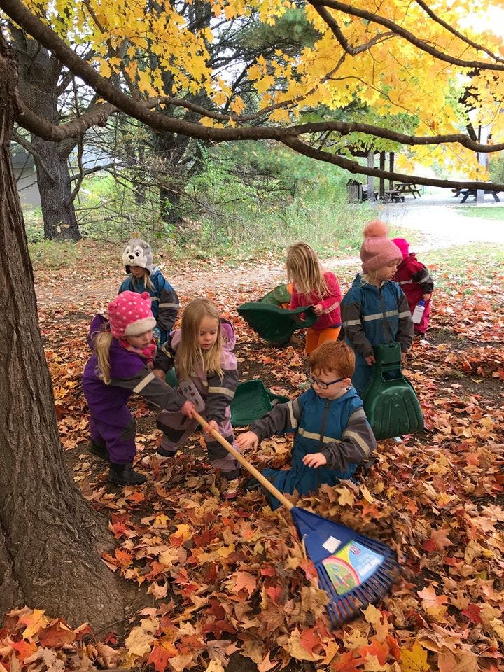 Children raking and playing in autumn leaves