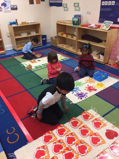 Three children playing on a colorful rug in a classroom