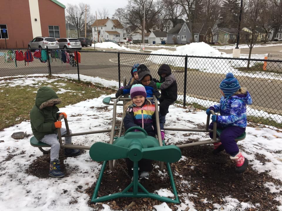 Children playing on a seesaw in a snowy playground
