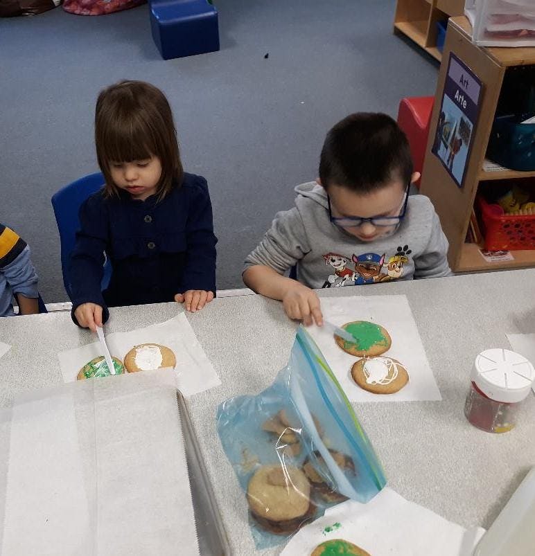 Two children decorating cookies at a table