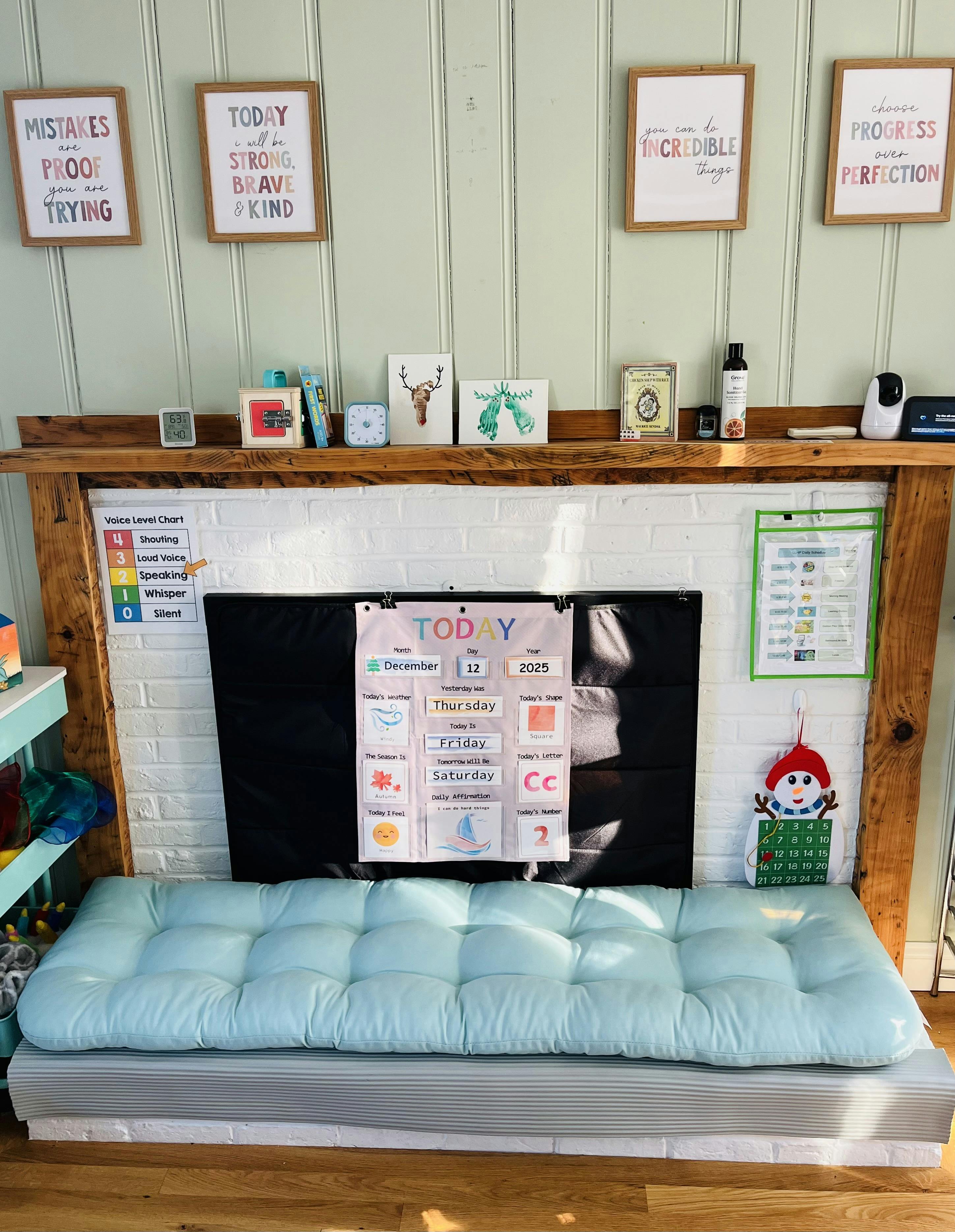 Fireplace with a light blue cushion on the hearth and various framed art on the mantel