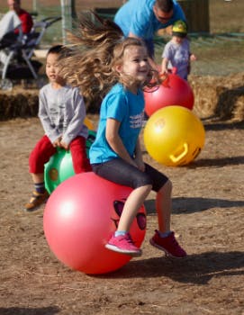 Children bouncing on hopper balls outdoors