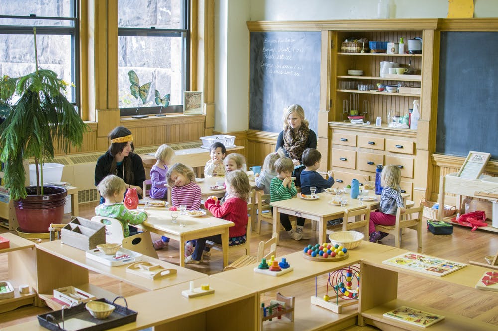 Adults and children sitting at tables in a classroom