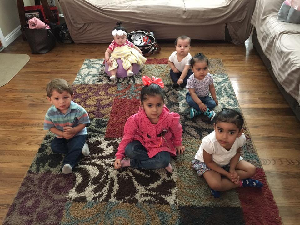 Five children and one baby sitting on a rug