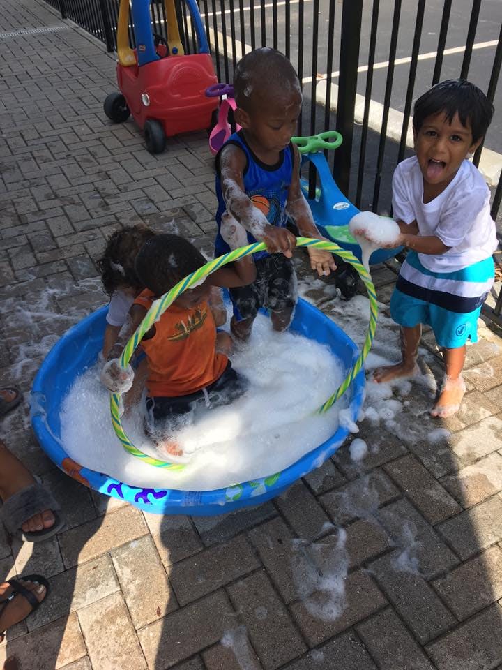 Three children playing in a bubble-filled kiddie pool