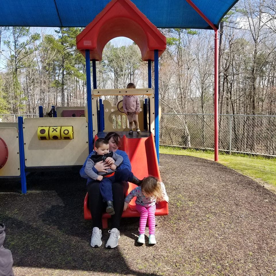 Person with two children on a playground slide