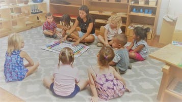 Adult and children sitting on a rug in a classroom