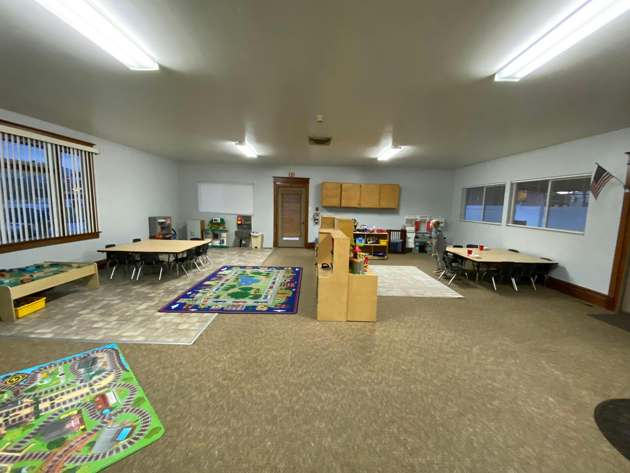 Empty classroom with tables, rugs, and play areas