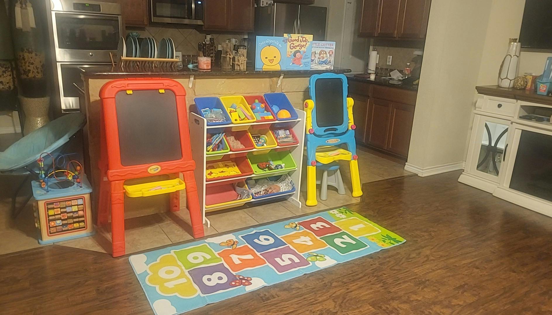 Children's play area with easels, toy organizer, and hopscotch rug