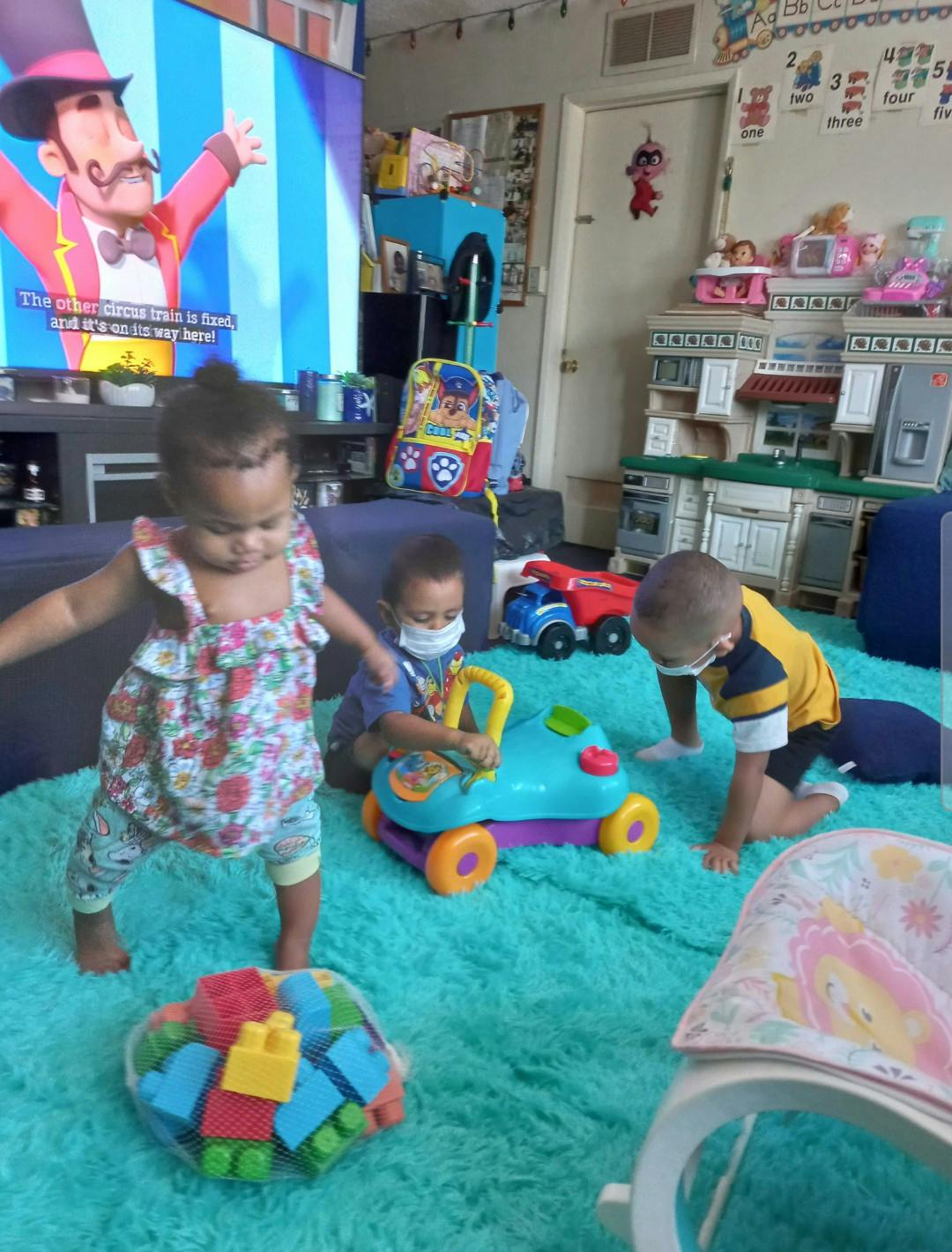 Three children playing with toys on a rug