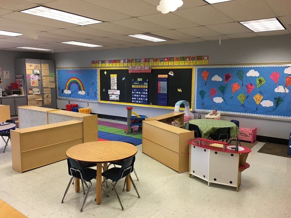 Empty classroom with small tables and chairs, colorful bulletin boards