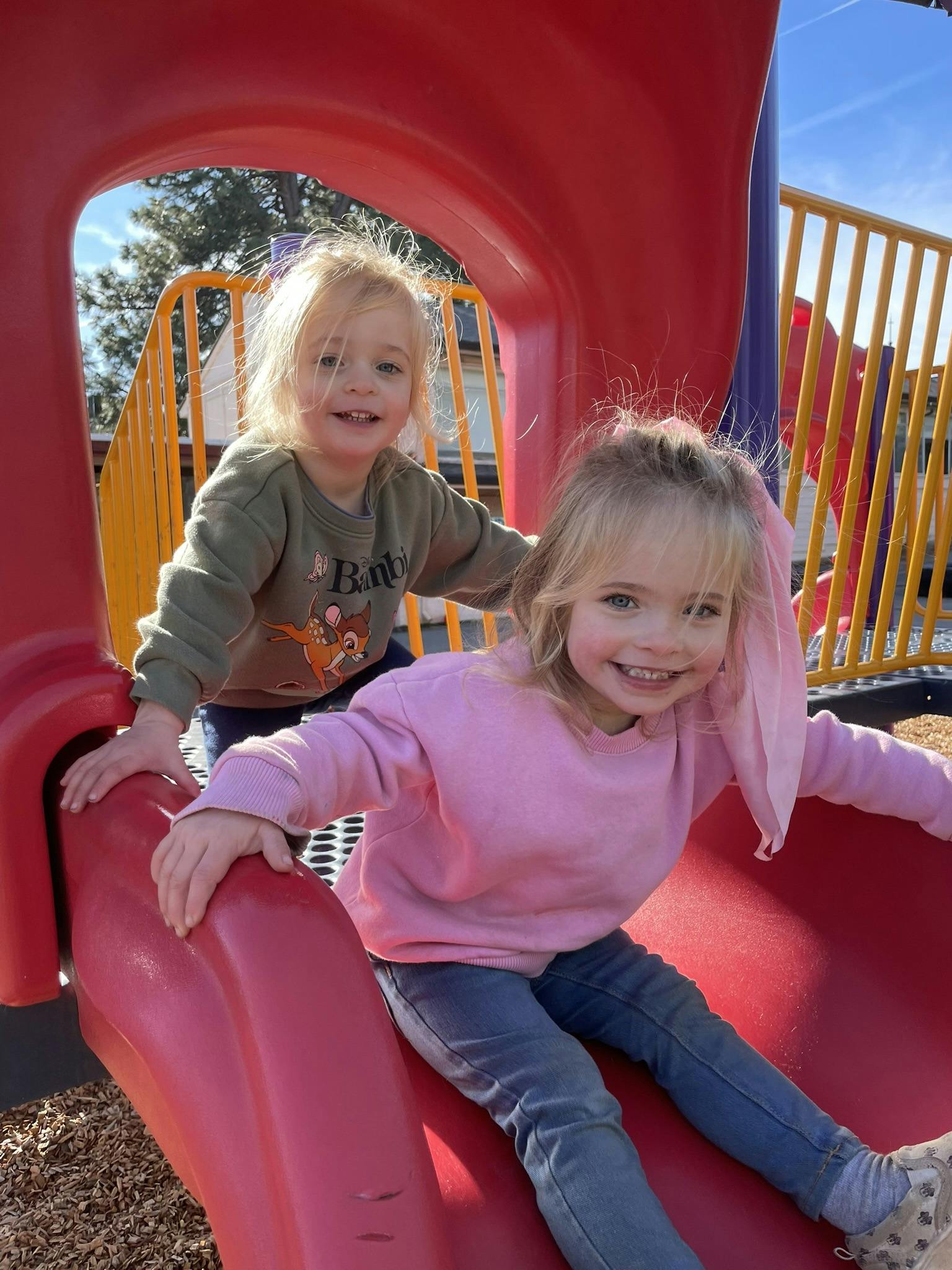 Two children on a red playground slide