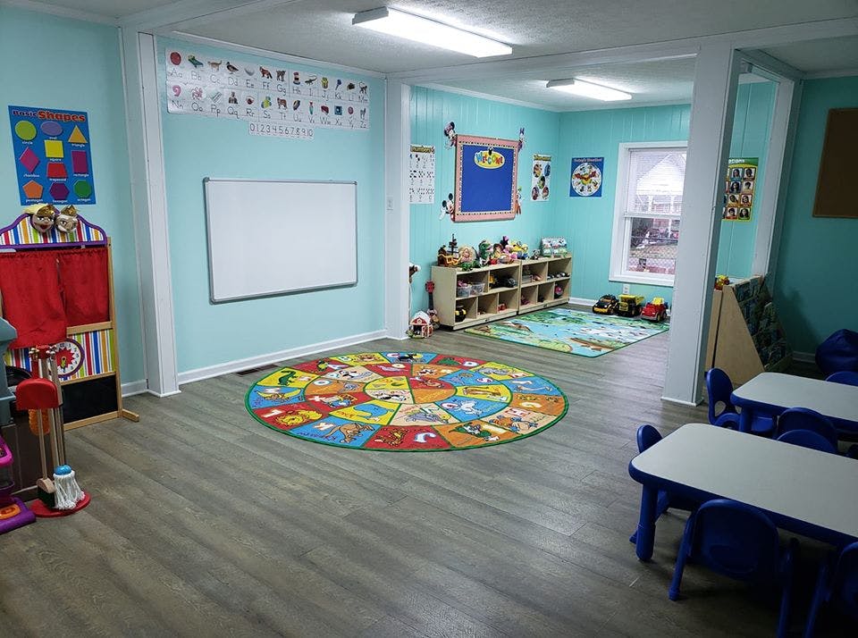 Playroom with colorful rugs, small tables, and a puppet theater