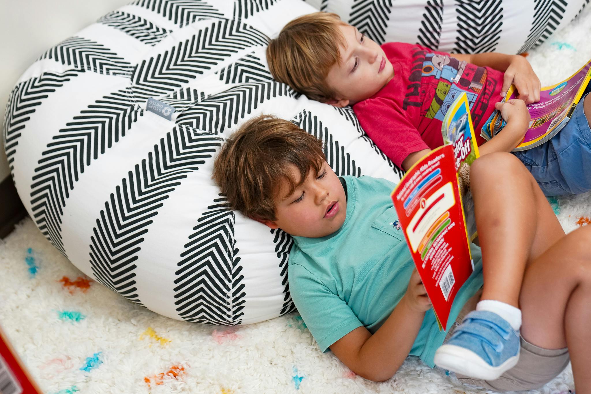 Two children lying on pillows and reading books