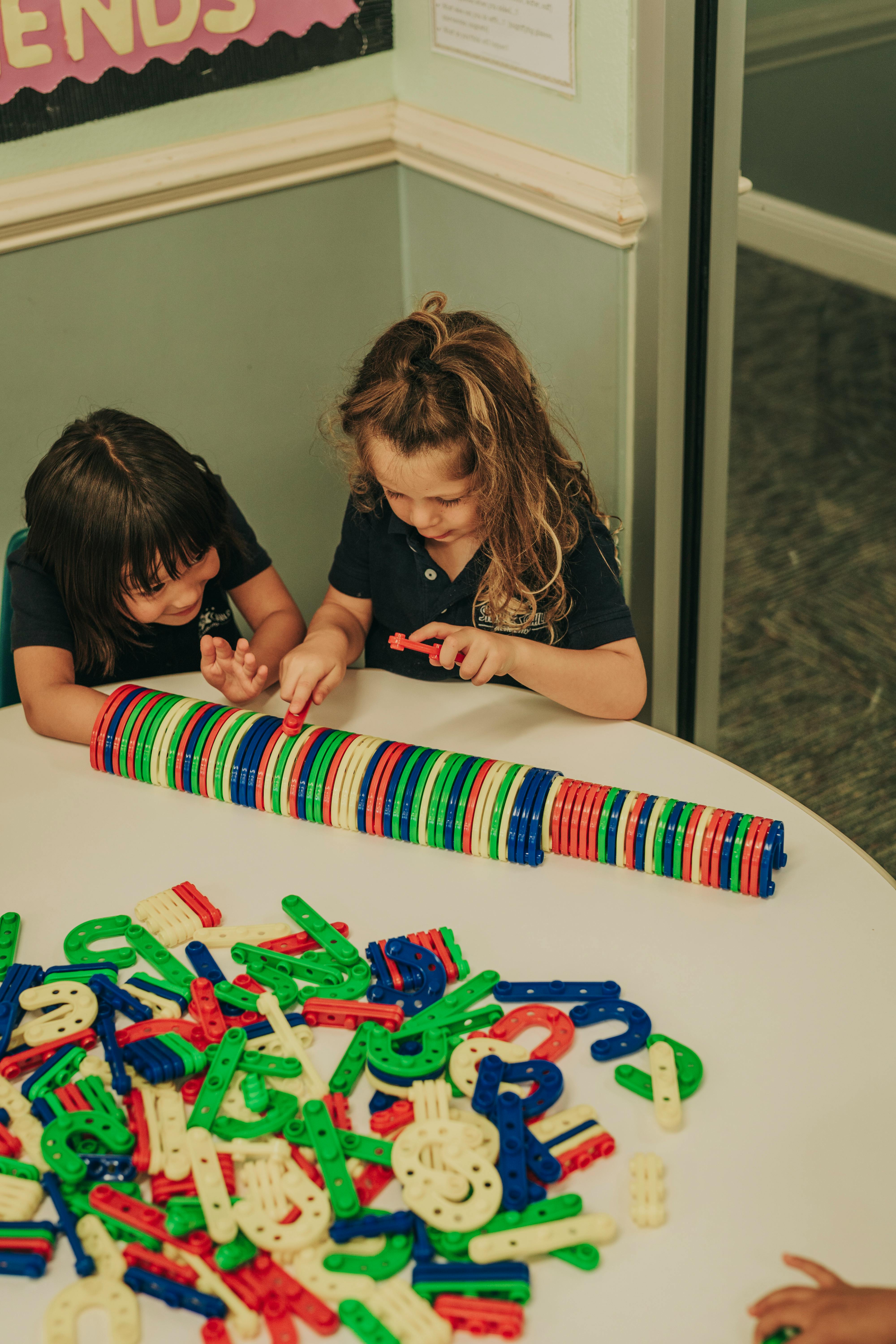 Two children playing with colorful building blocks on a table