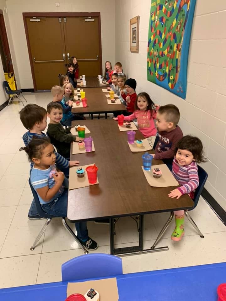 Children sitting at tables with cupcakes and drinks