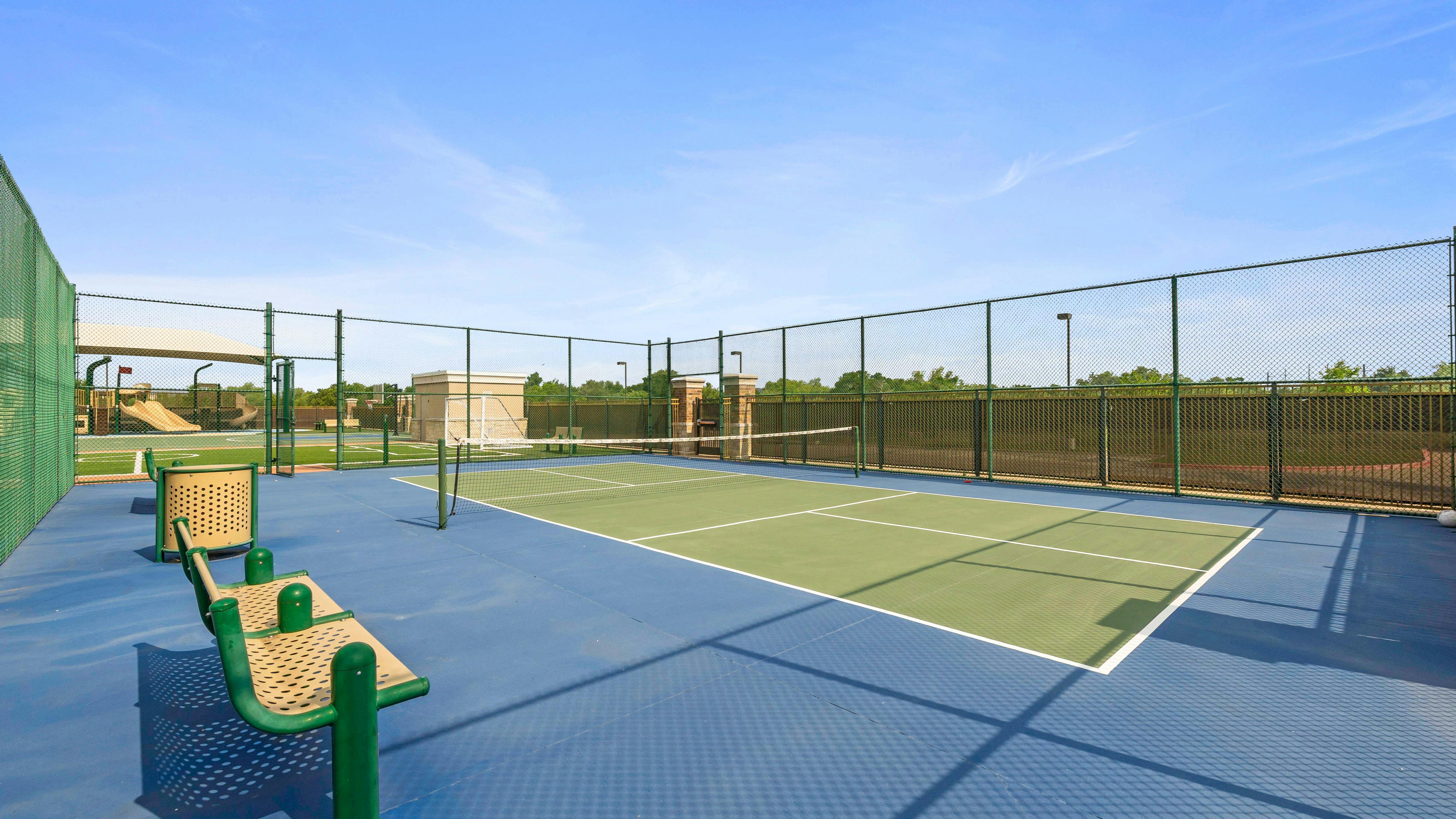 Empty blue and green outdoor tennis court with a chain link fence