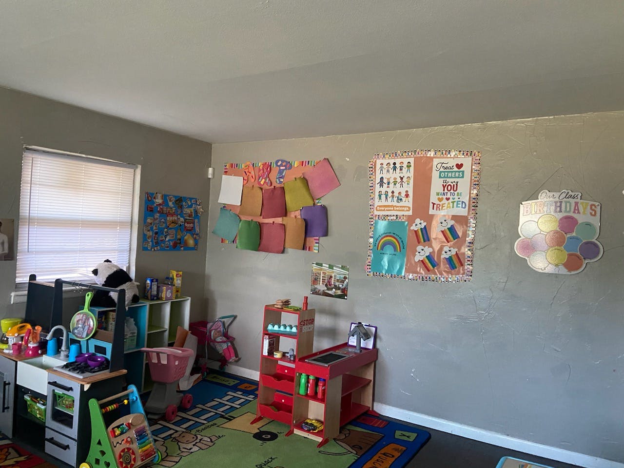 Playroom with toys, play kitchen, and colorful artwork on the wall