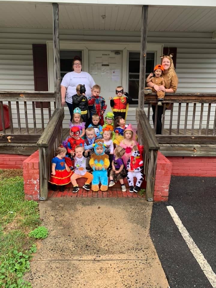 Two adults and multiple children in costumes on a porch