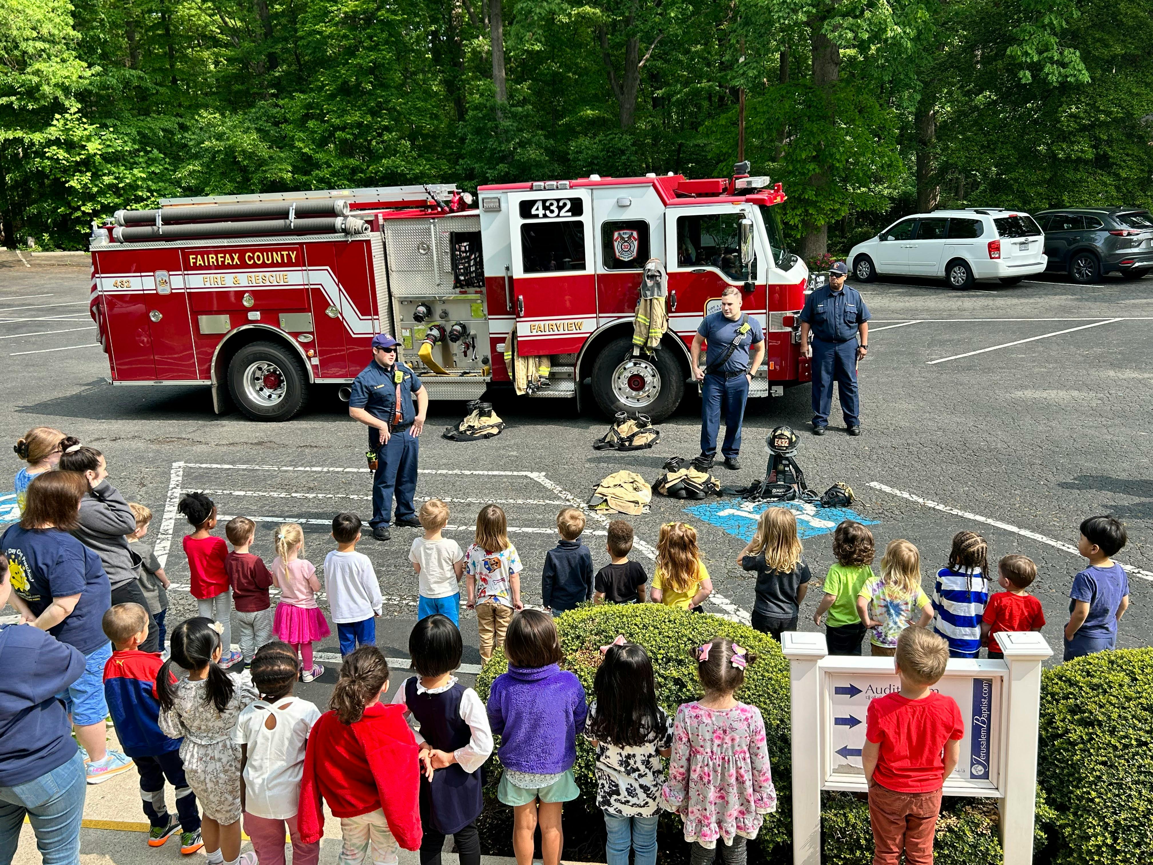 Children and adults gathered around a fire truck with firefighters