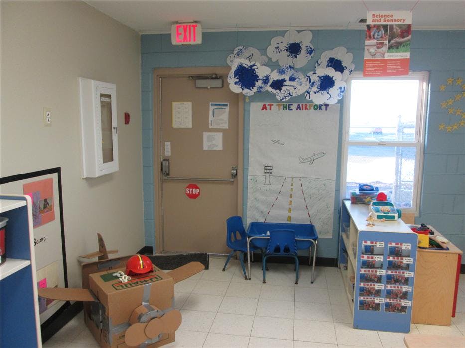 Children's play area with a cardboard airplane and an airport drawing