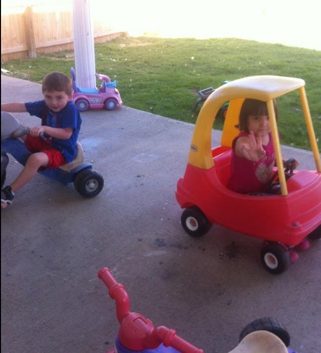 Child on a ride-on toy and another child in a toy car