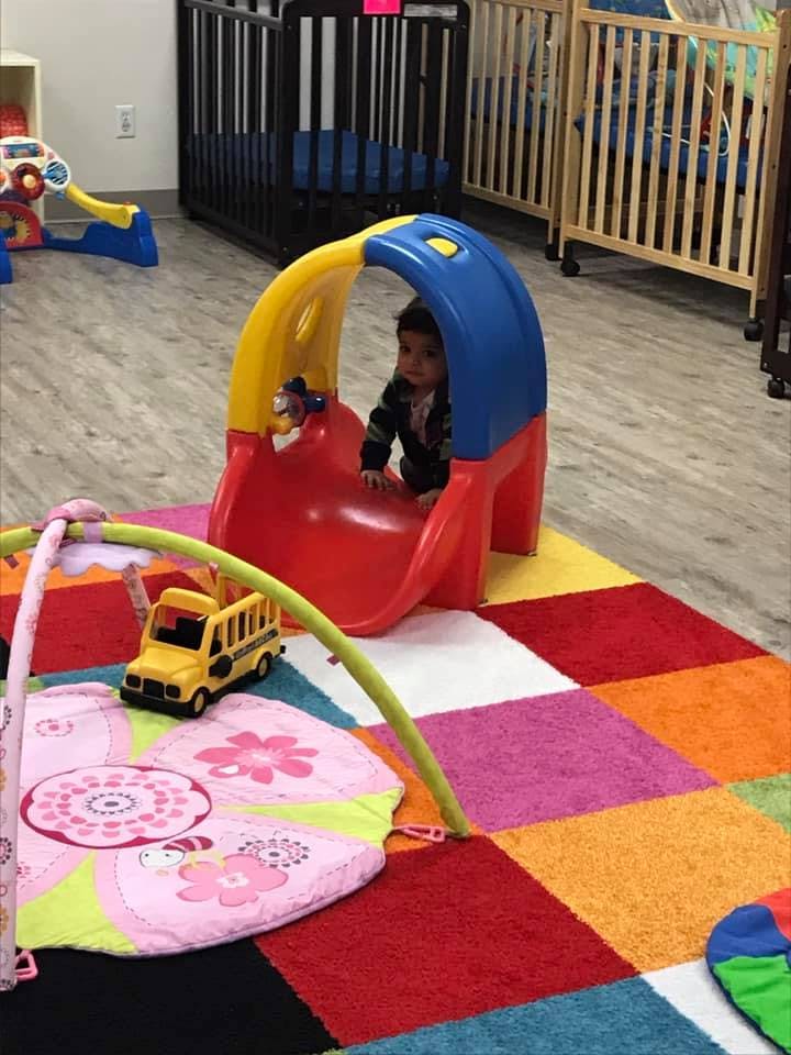 Child in a red, blue, and yellow play slide on a colorful rug