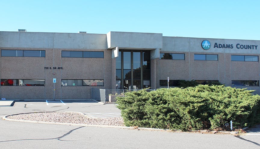 Adams County building exterior with bushes in foreground