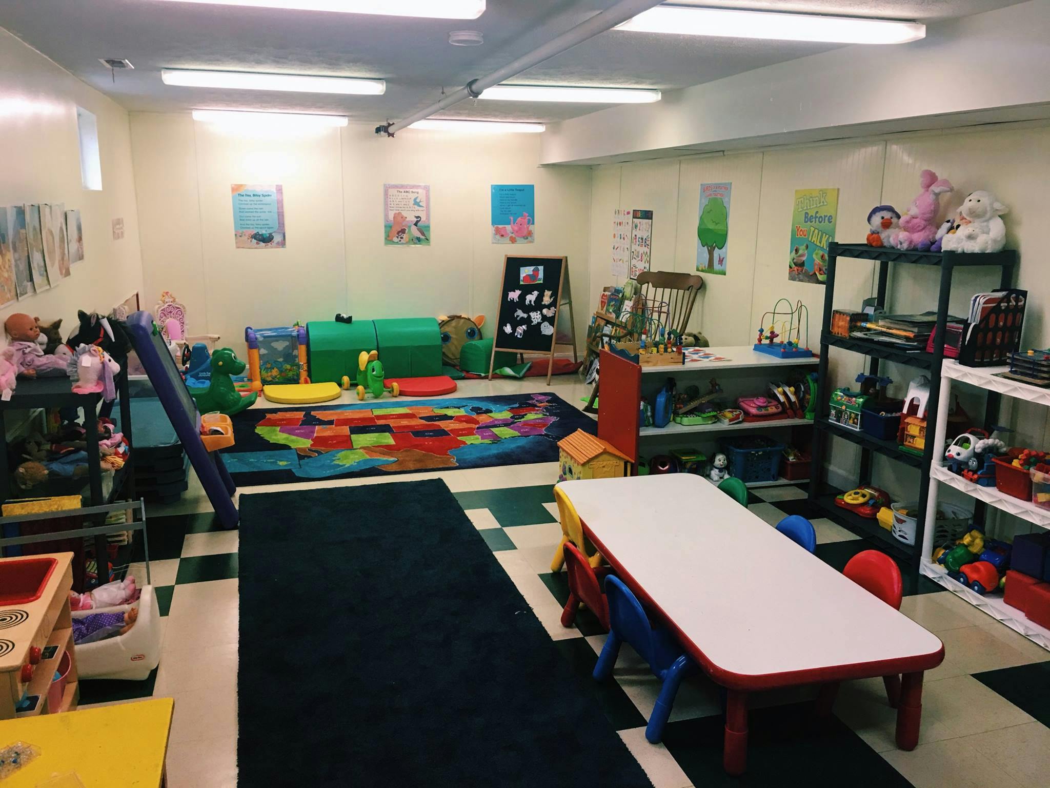 Playroom with colorful rug, slide, and tables