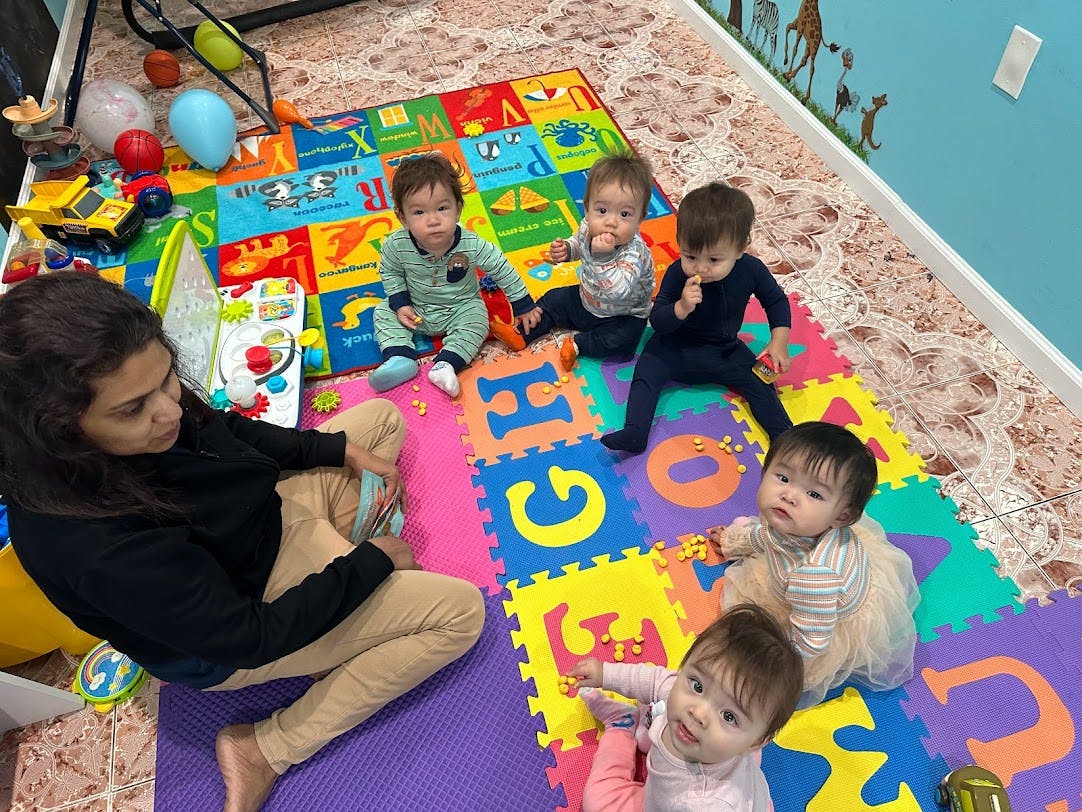 A person sitting with five babies on colorful alphabet playmats