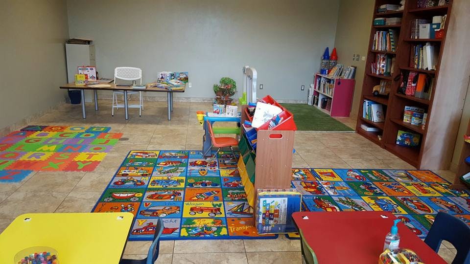 Playroom with colorful rugs, small tables, and bookshelves