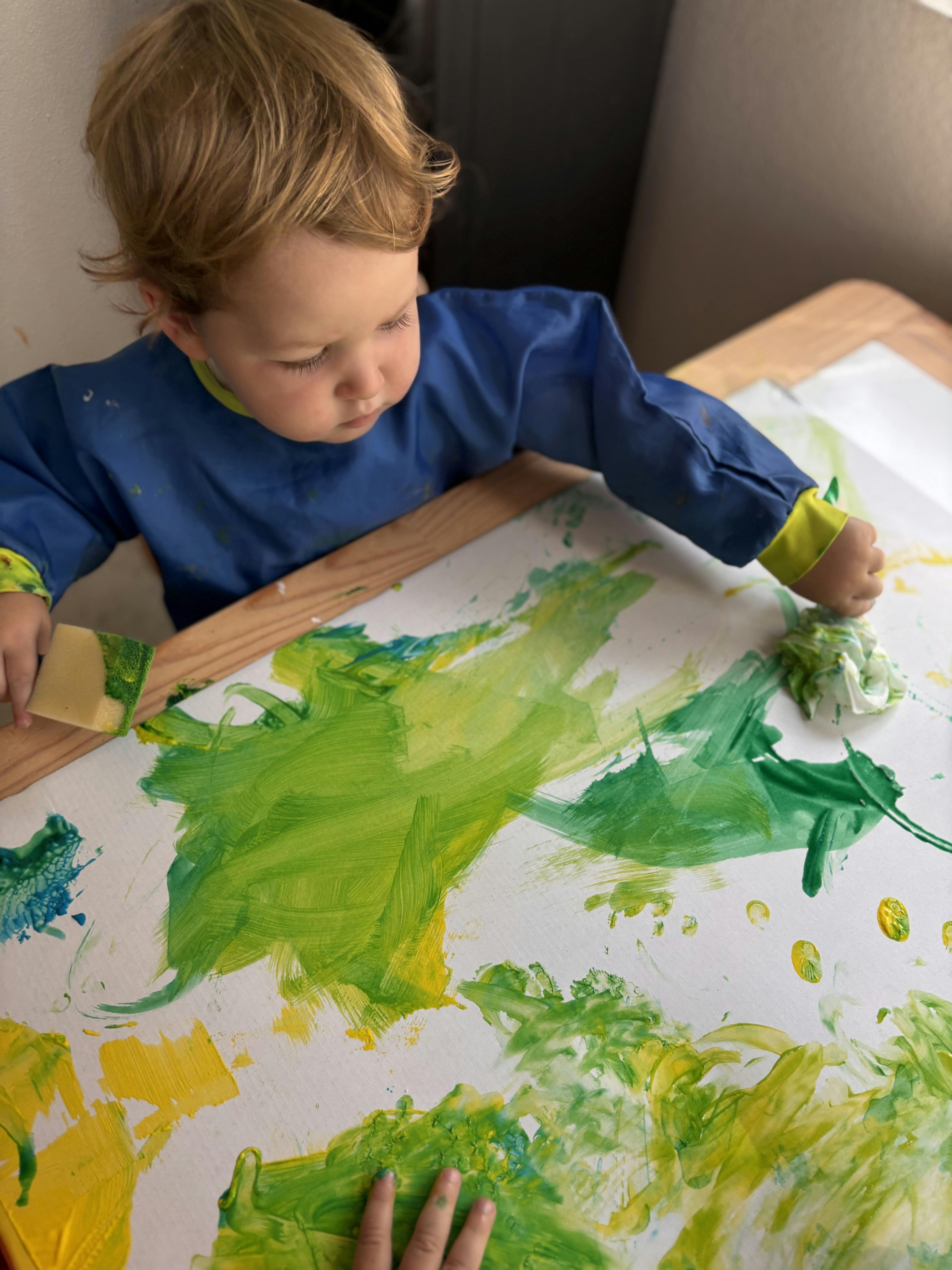 Child painting on paper with a sponge
