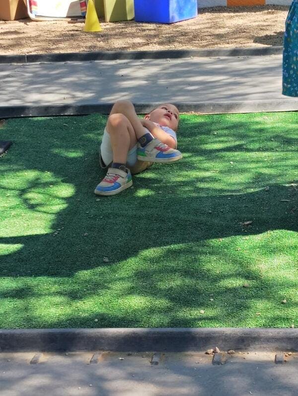 Child lying on artificial grass with legs bent