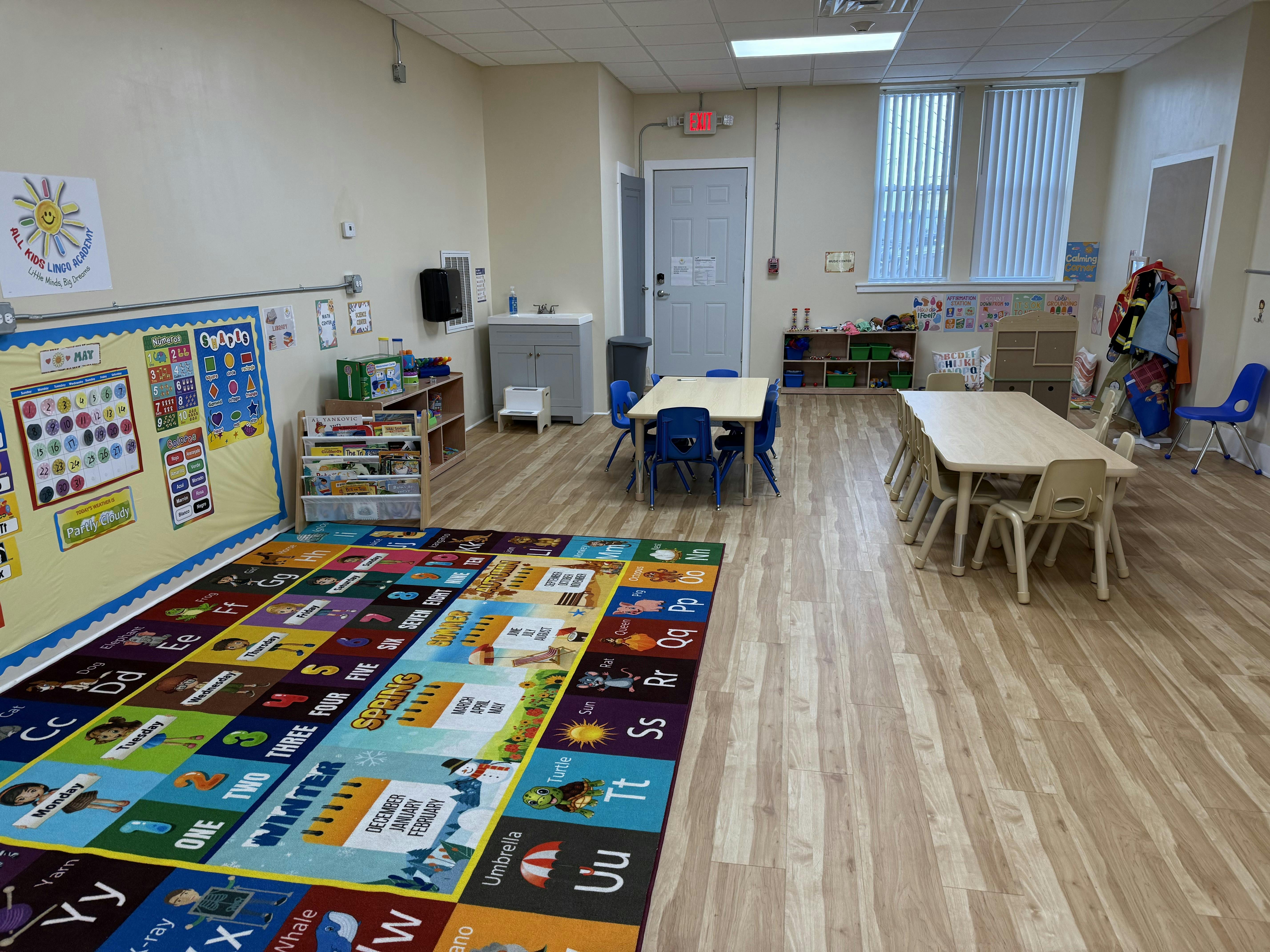 Classroom with colorful alphabet rug and small tables with chairs